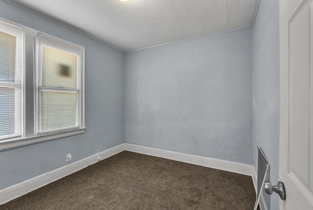 spare room with dark carpet and a textured ceiling