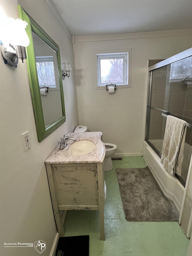 full bathroom with vanity, bath / shower combo with glass door, crown molding, and toilet