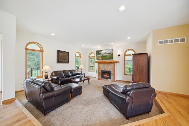 living room featuring a wealth of natural light, light hardwood / wood-style flooring, and a tiled fireplace