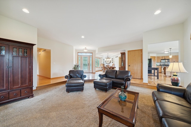 living room featuring light colored carpet and an inviting chandelier