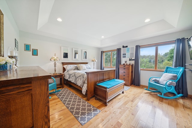 bedroom with a tray ceiling and light hardwood / wood-style flooring