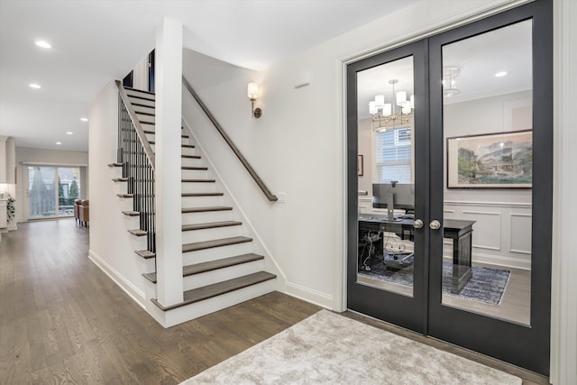 foyer entrance with dark hardwood / wood-style floors, an inviting chandelier, and french doors