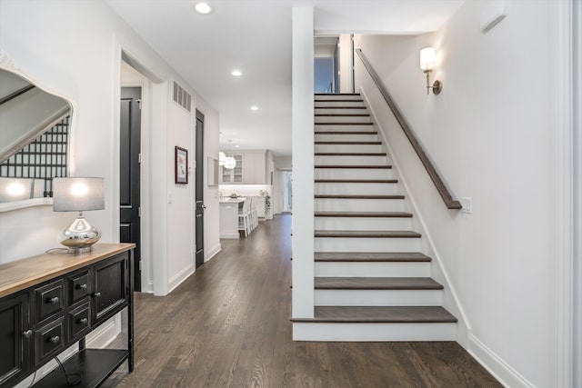 staircase featuring wood-type flooring and an inviting chandelier