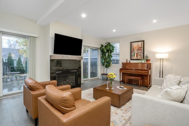 living room with beamed ceiling, a healthy amount of sunlight, and light hardwood / wood-style floors