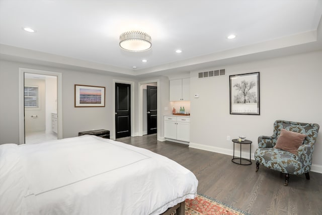 bedroom featuring connected bathroom, a raised ceiling, and dark wood-type flooring