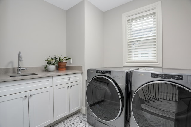 clothes washing area featuring washing machine and dryer, sink, and cabinets