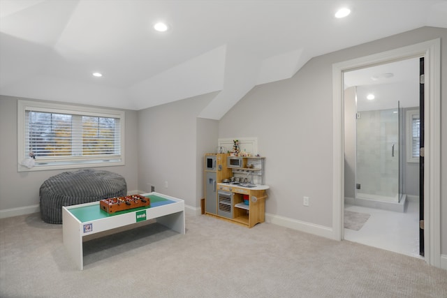 carpeted bedroom featuring ensuite bath and lofted ceiling