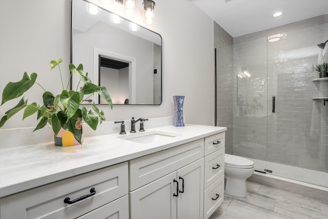 bathroom featuring vanity, a shower with shower door, and toilet