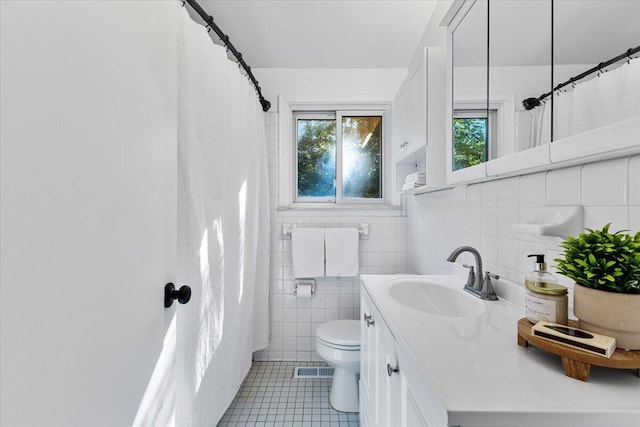 bathroom featuring tile patterned flooring, vanity, toilet, and tile walls