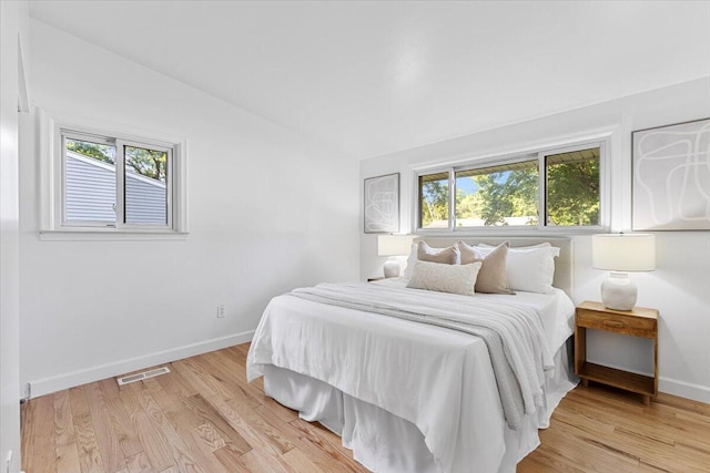 bedroom with light hardwood / wood-style floors and lofted ceiling