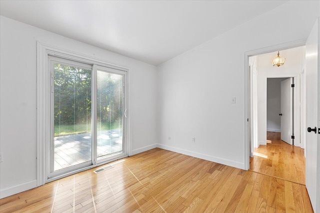 spare room with light hardwood / wood-style floors and an inviting chandelier