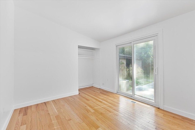 spare room with lofted ceiling and light wood-type flooring