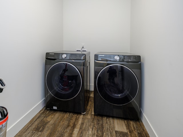 laundry area featuring dark wood-style floors, laundry area, washing machine and dryer, and baseboards