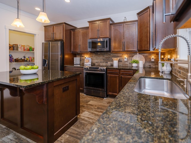 kitchen featuring pendant lighting, decorative backsplash, sink, and stainless steel appliances