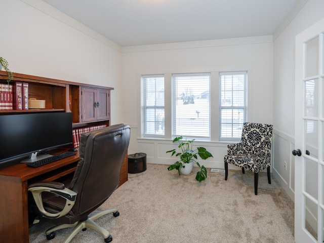 office space with a wainscoted wall, light carpet, and a decorative wall