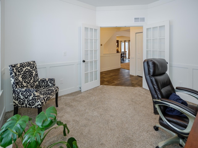 carpeted office space featuring wainscoting, visible vents, a decorative wall, and french doors