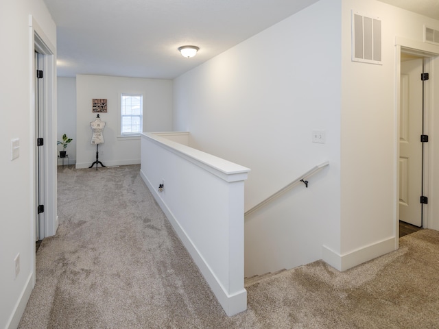 corridor featuring baseboards, visible vents, light carpet, and an upstairs landing