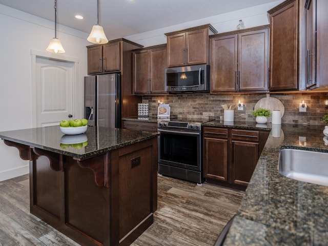 kitchen with stainless steel appliances, dark stone counters, and decorative backsplash