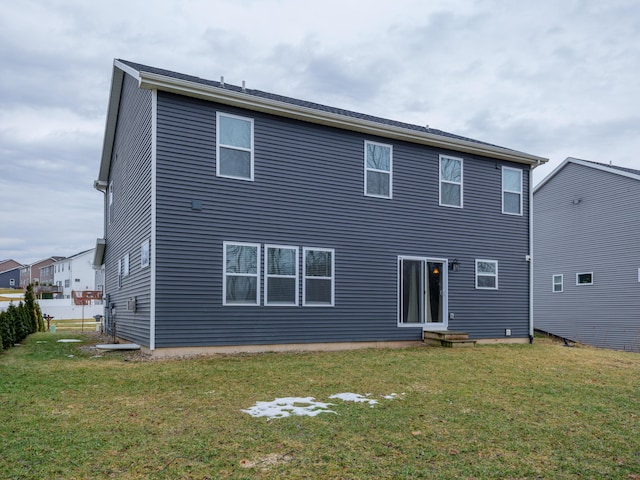 back of property featuring entry steps and a lawn