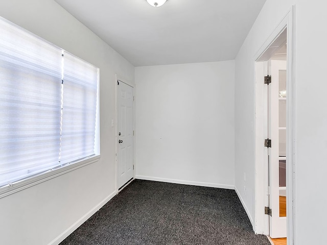 spare room with dark carpet