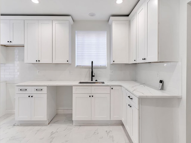 kitchen featuring backsplash, light stone counters, white cabinetry, and sink