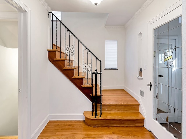 stairway featuring hardwood / wood-style floors and ornamental molding