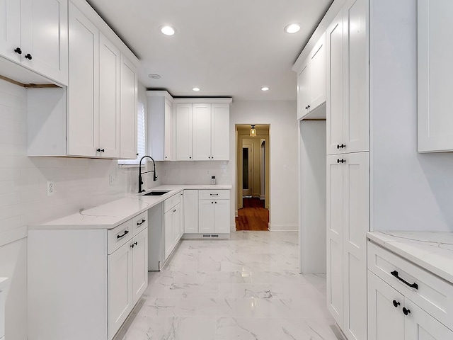 kitchen with white cabinetry, light stone counters, tasteful backsplash, and sink