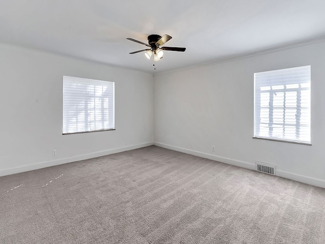 carpeted empty room with a wealth of natural light, ceiling fan, and crown molding