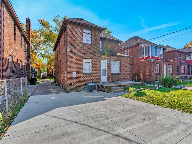 view of front of home with central AC unit and a front yard