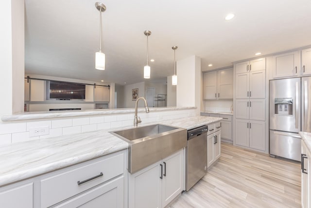 kitchen with gray cabinets, hanging light fixtures, light wood-type flooring, and appliances with stainless steel finishes