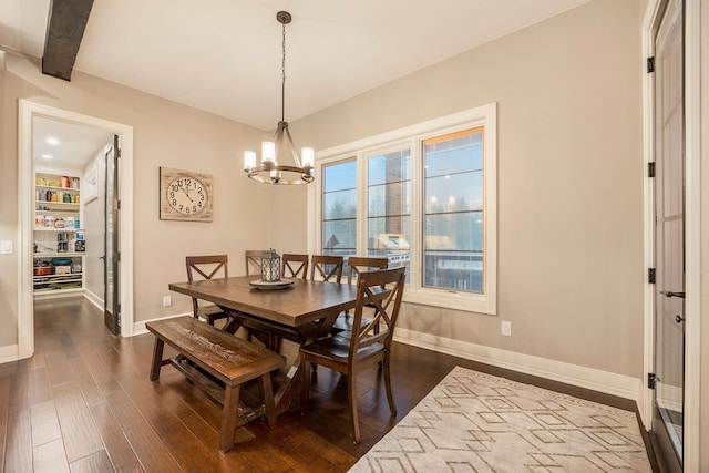 dining room featuring beam ceiling, an inviting chandelier, a wealth of natural light, and dark wood-type flooring