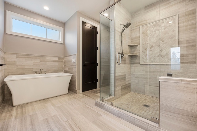 bathroom featuring shower with separate bathtub and tile walls