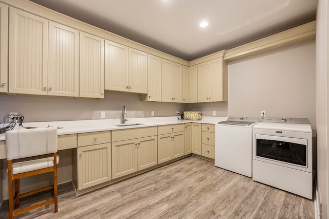 laundry area with light hardwood / wood-style floors, cabinets, sink, and washing machine and clothes dryer