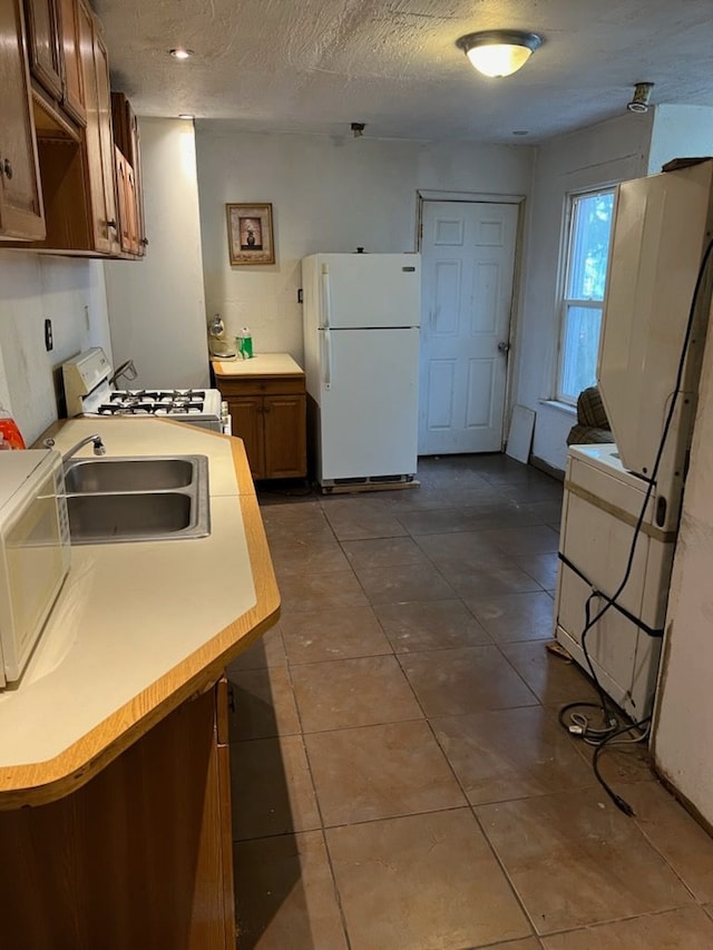 kitchen featuring a textured ceiling, white appliances, and sink