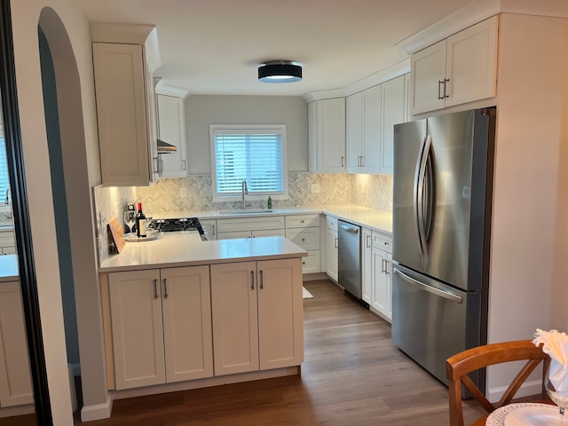 kitchen with sink, white cabinetry, light wood-type flooring, stainless steel appliances, and decorative backsplash