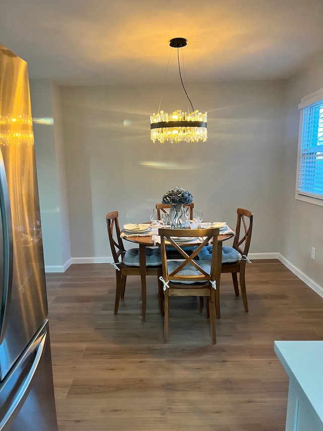 dining space featuring dark wood-type flooring and an inviting chandelier