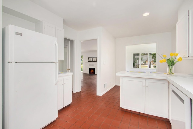 kitchen with white cabinets, kitchen peninsula, and white fridge