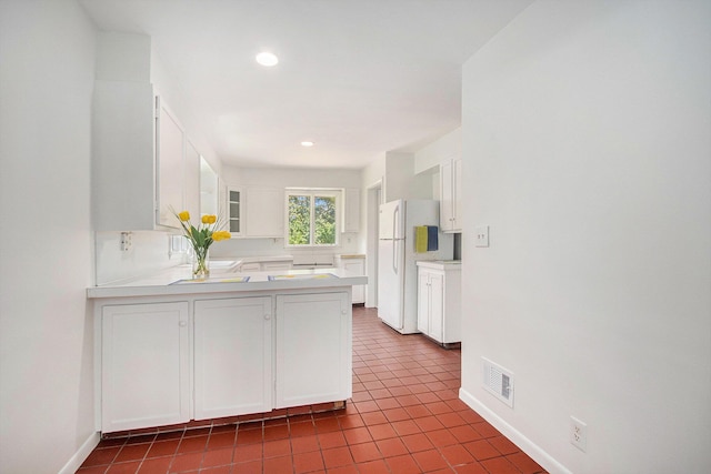 kitchen featuring tile patterned floors, kitchen peninsula, white cabinetry, and white fridge