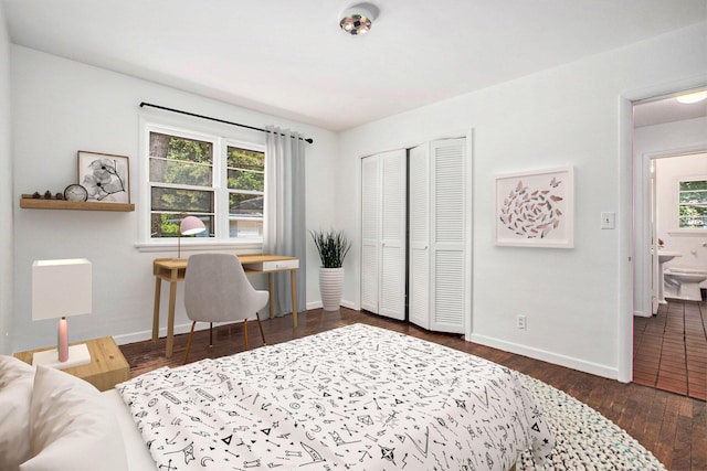 bedroom featuring a closet, dark hardwood / wood-style floors, ensuite bath, and multiple windows