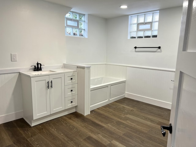 bathroom with hardwood / wood-style floors, vanity, and a tub to relax in