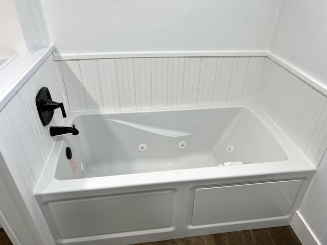 bathroom with hardwood / wood-style flooring and a tub to relax in