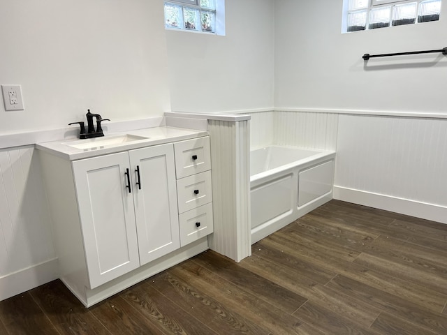 bathroom with hardwood / wood-style flooring, vanity, and a tub to relax in