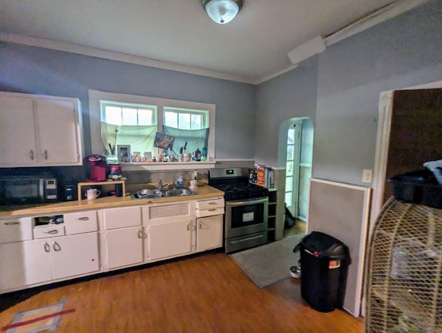 kitchen with ornamental molding, stainless steel range, sink, white cabinets, and light hardwood / wood-style floors