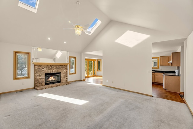 unfurnished living room featuring a fireplace, a skylight, high vaulted ceiling, and light carpet