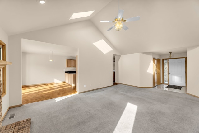 unfurnished living room featuring high vaulted ceiling, a skylight, light colored carpet, and ceiling fan