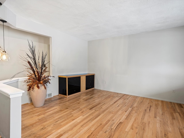 empty room featuring light wood-type flooring and a textured ceiling