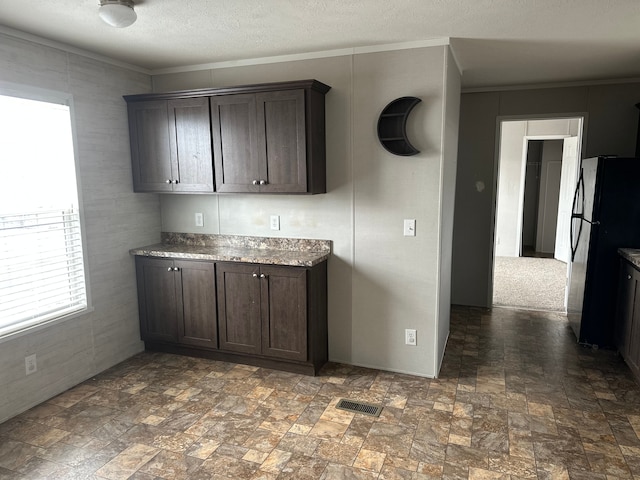 kitchen featuring dark brown cabinetry, fridge, and ornamental molding