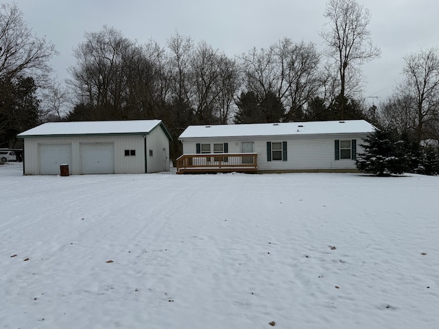 snow covered rear of property with a garage, an outdoor structure, and a wooden deck