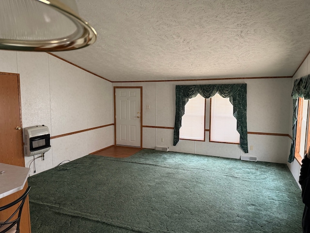 carpeted empty room featuring a textured ceiling, heating unit, and crown molding