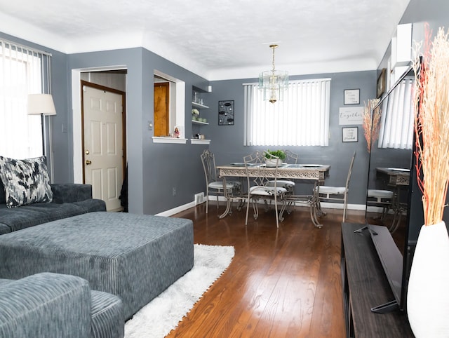 living room featuring a wealth of natural light, dark hardwood / wood-style flooring, and an inviting chandelier